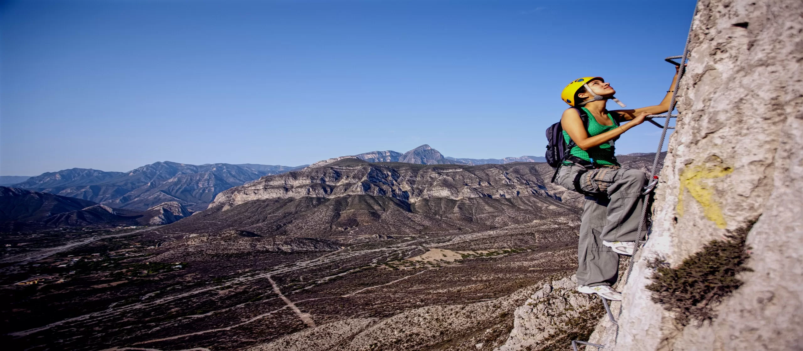 Ecoproparks. Persona escalando con vista a montañas en el fondo.
